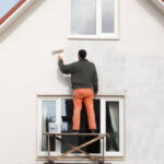 construction worker is painting a wall with a roller