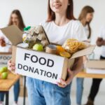 smiley-female-volunteer-holding-donations-box-with-food_23-2148732648