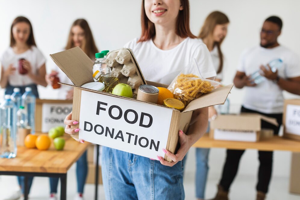 smiley-female-volunteer-holding-donations-box-with-food_23-2148732648