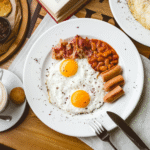 top-view-english-breakfast-fried-egg-beans-sausages-bacon-cup-coffee-table-min-scaled