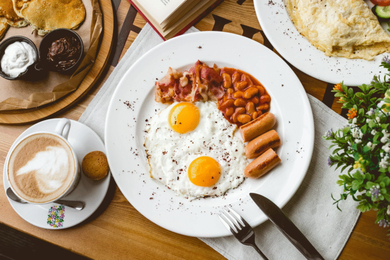 top-view-english-breakfast-fried-egg-beans-sausages-bacon-cup-coffee-table-min-scaled
