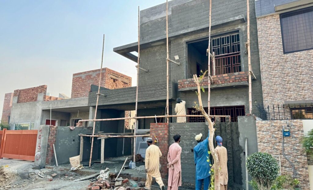 An image showing a house under construction with several workers present. Looking for the best construction services in DHA Lahore? Consider reputable local companies with a strong portfolio and positive client reviews.