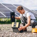 Man worker in the firld by the solar panels
