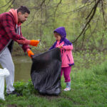 Dad and daughter, with garbage bags, clean the environment of garbage.