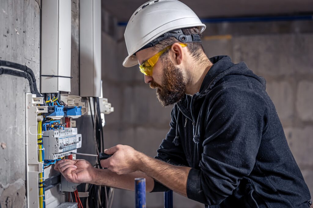 a-male-electrician-works-in-a-switchboard-with-an-electrical-connecting-cable-