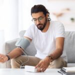 Young,Arab,Man,Sitting,On,Couch,,Checking,Blood,Pressure,And