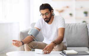Young,Arab,Man,Sitting,On,Couch,,Checking,Blood,Pressure,And