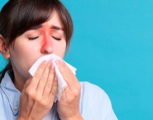 A-woman-with-inflamed-sinus-areas-blowing-her-nose-indicating-chronic-sinusitis-551x431