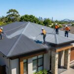Workers in safety harnesses performing a Colorbond metal roof restoration on a modern Sydney home under a bright blue sky (1)