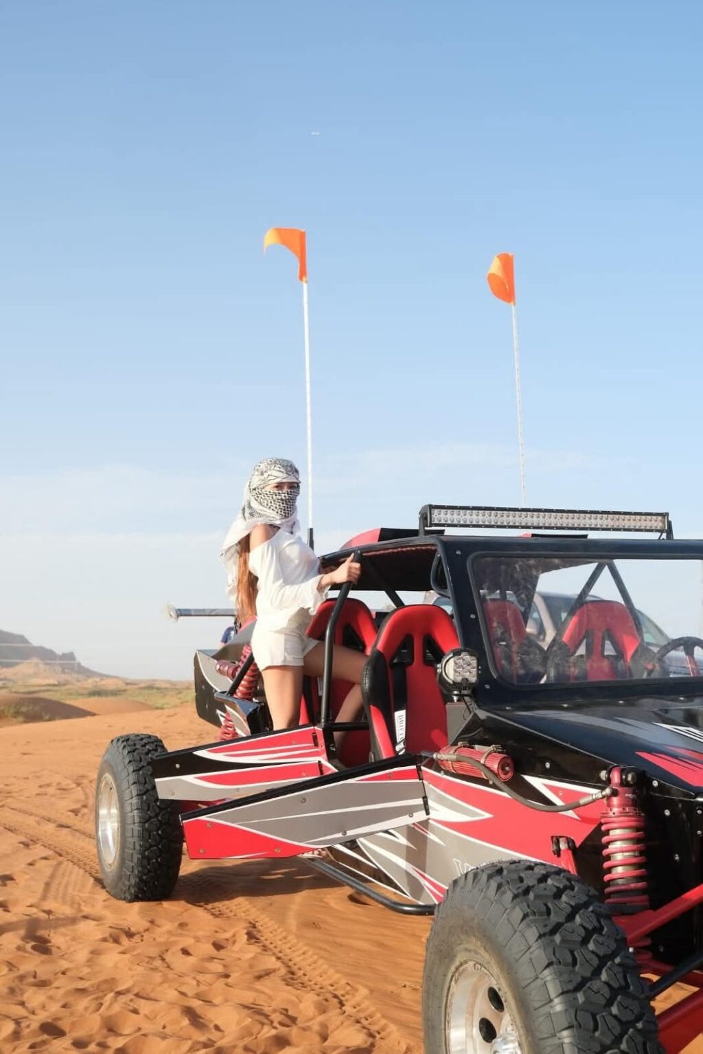 Tourists driving a powerful dune buggy across the golden sand dunes during a Dune Buggy Dubai adventure.