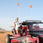 Tourists driving a powerful dune buggy across the golden sand dunes during a Dune Buggy Dubai adventure.
