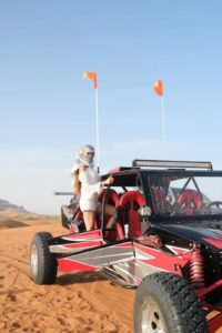 Tourists driving a powerful dune buggy across the golden sand dunes during a Dune Buggy Dubai adventure.