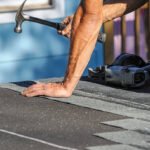 close up on worker using hammer repairing roof