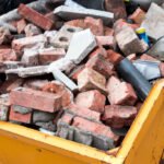 Yellow metal skip full of old bricks