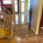 Professional technician using a dustless hardwood floor refinishing machine in a Calgary home.