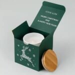 Green Christmas candle gift box with a festive reindeer design, white candle, and wooden lid.